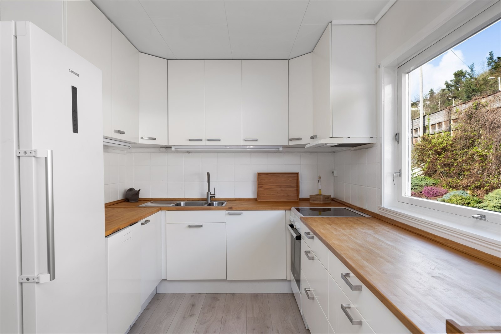 Lyst og romslig kjøkken med tidløse farger og overflater. Galleribilde