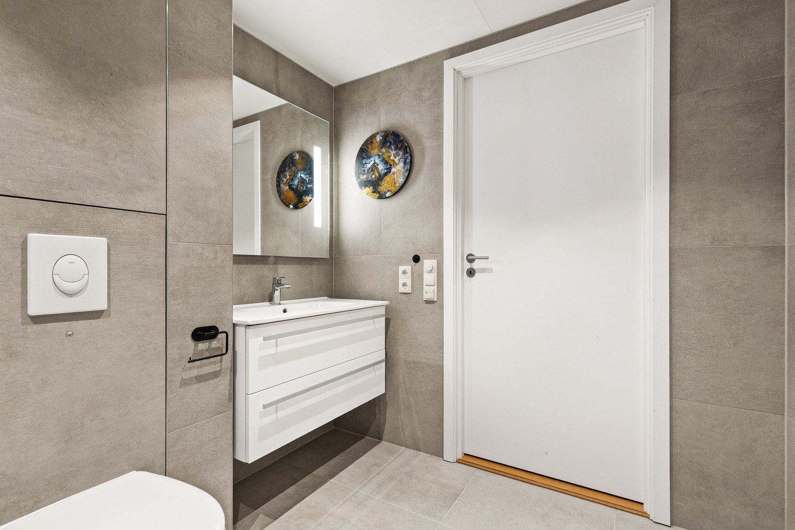 Det er montert en vegghengt servantinnredning med skuffer og en ovenpåliggende servant med ett-greps armatur. Over servanten er det speil med sidelys Galleribilde