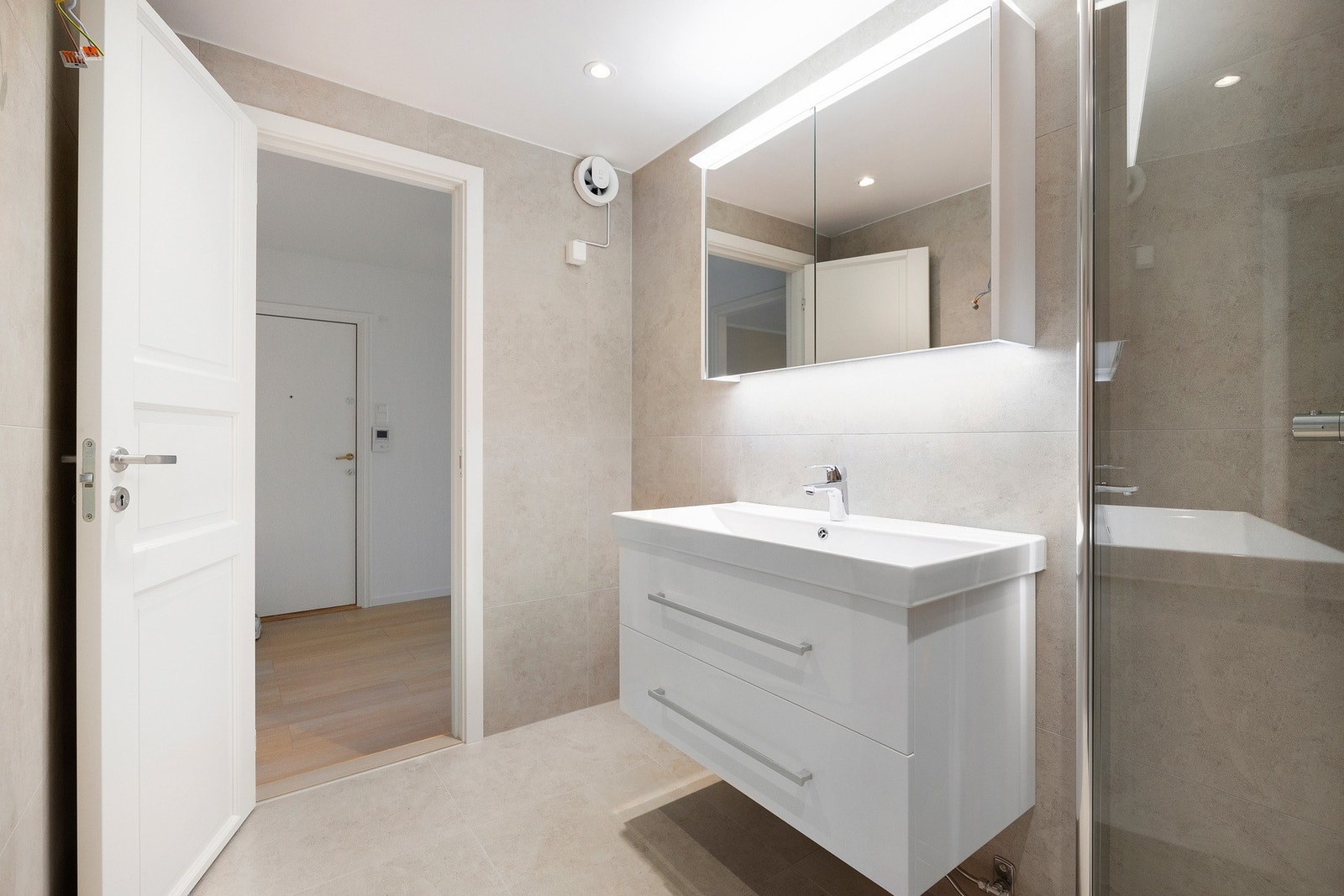 Badet er innredet med dusjhjørne (dusj rett på gulv), servantskap, speil på vegg, belysning og opplegg for vaskemaskin. Galleribilde