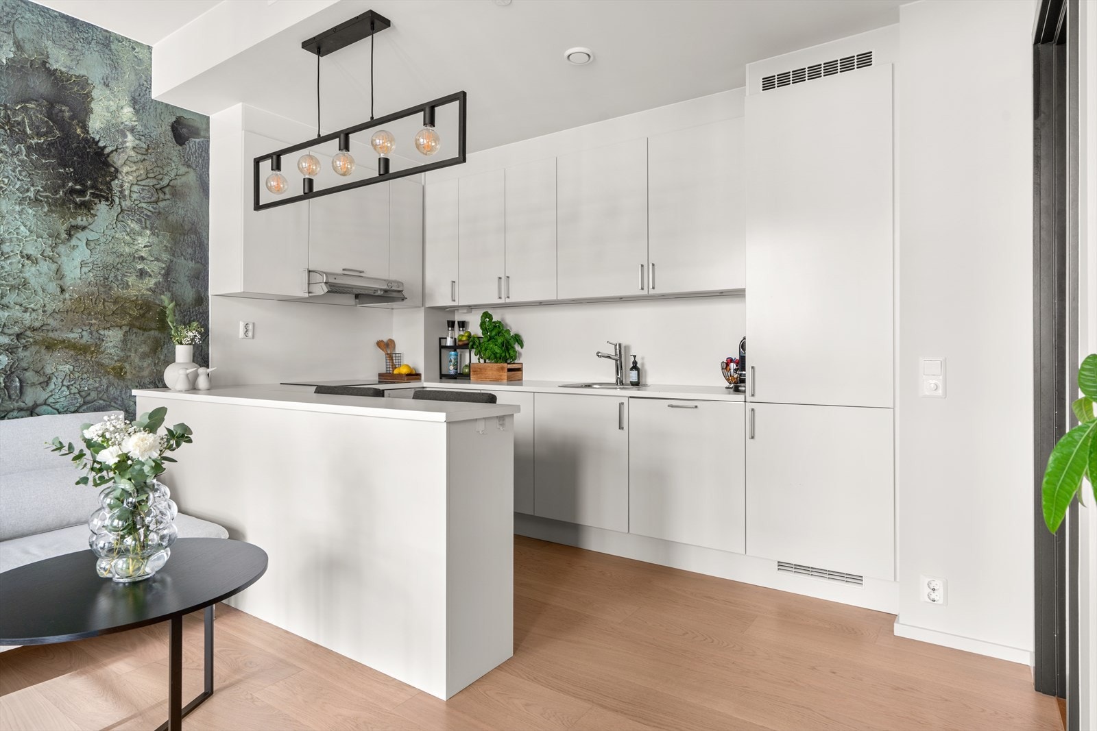 Tidløst Sigdal kjøkken innredet med hvite glatte fronter, malte flater over laminert benk og stålkum med ett-greps blandebatteri. Galleribilde