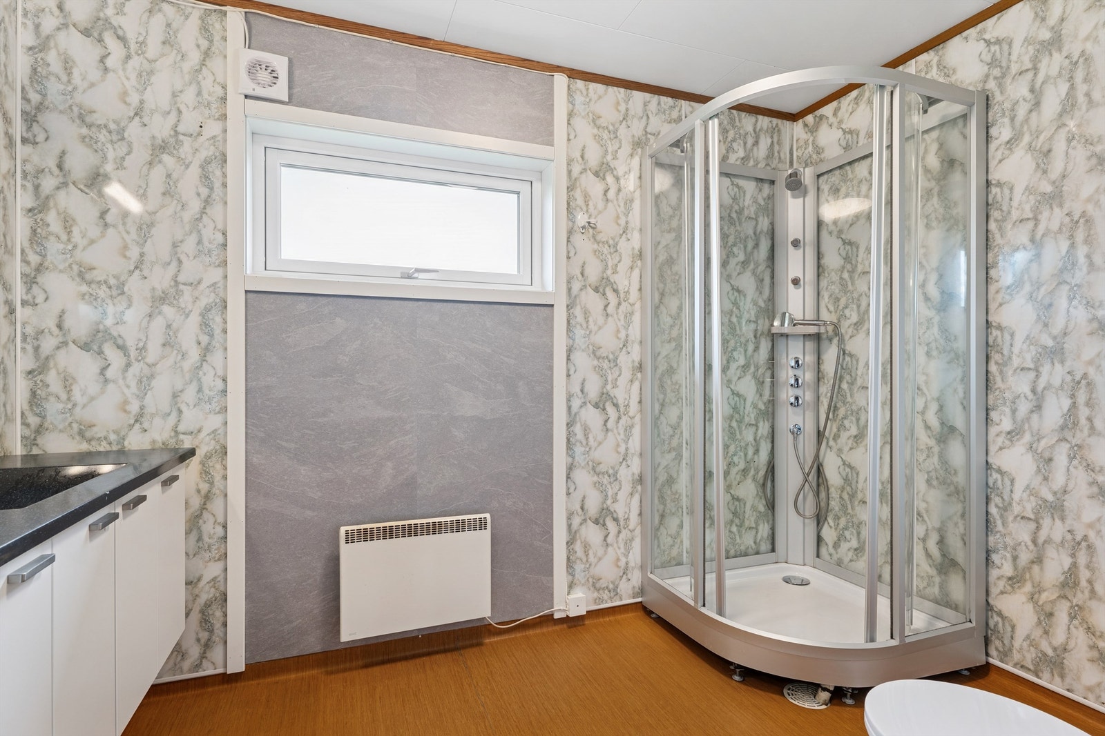 Her er det også opplegg for vaskemaskin. Gulvet er belagt med belegg, og veggene er kledd med baderomsplater. Galleribilde