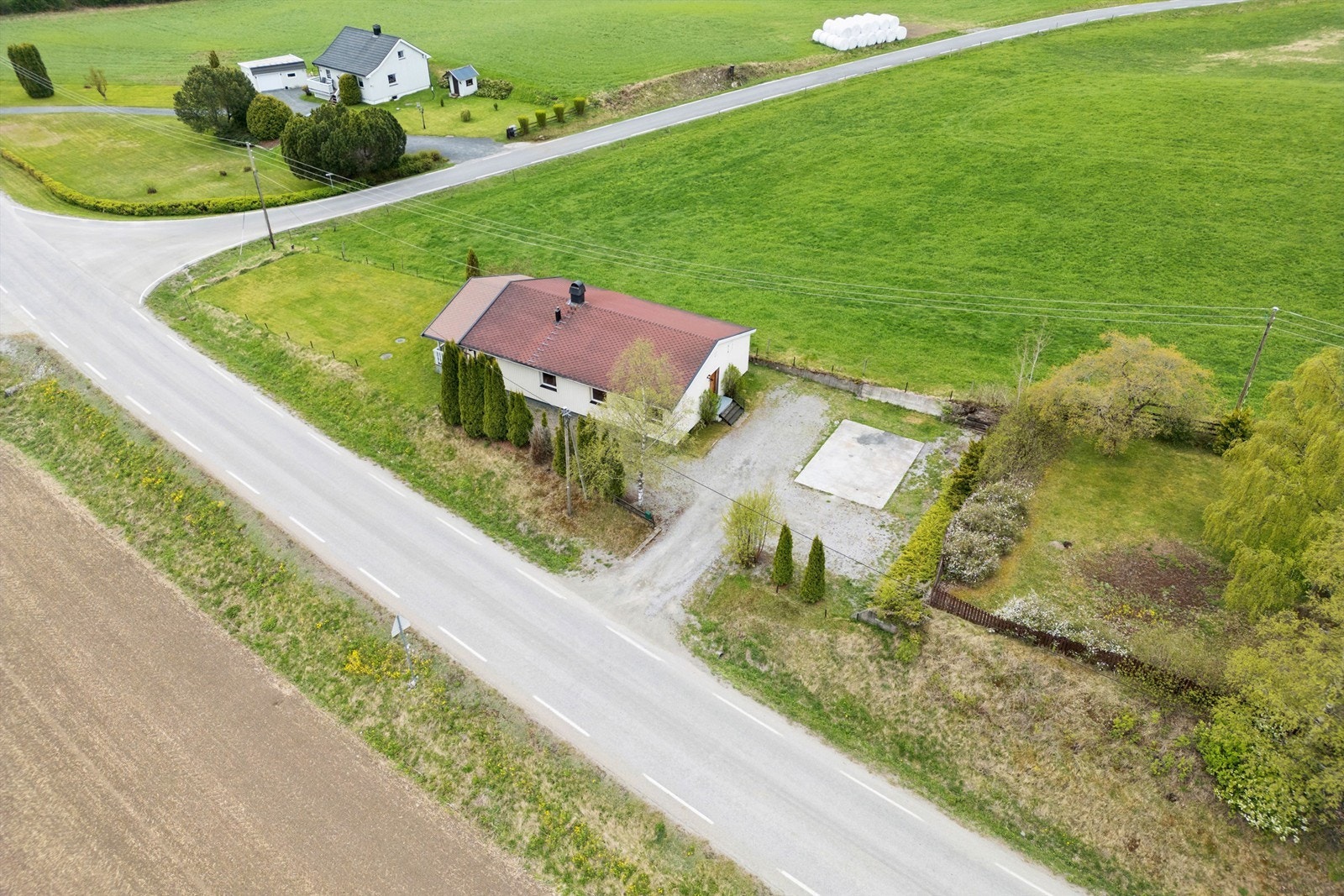 Tomten er pent opparbeidet med plen og prydvekster. Det er støttemur mot jordet på langsiden, samt mot nabo mot nord. Galleribilde