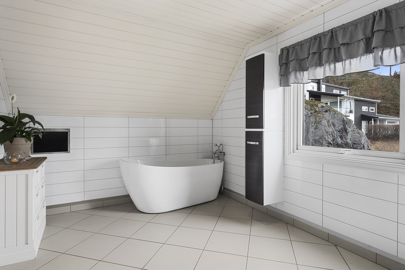 Badet er utstyrt med servant over skuffeinnredning, speil med belysning, dusjkabinett, badekar og toalett Galleribilde