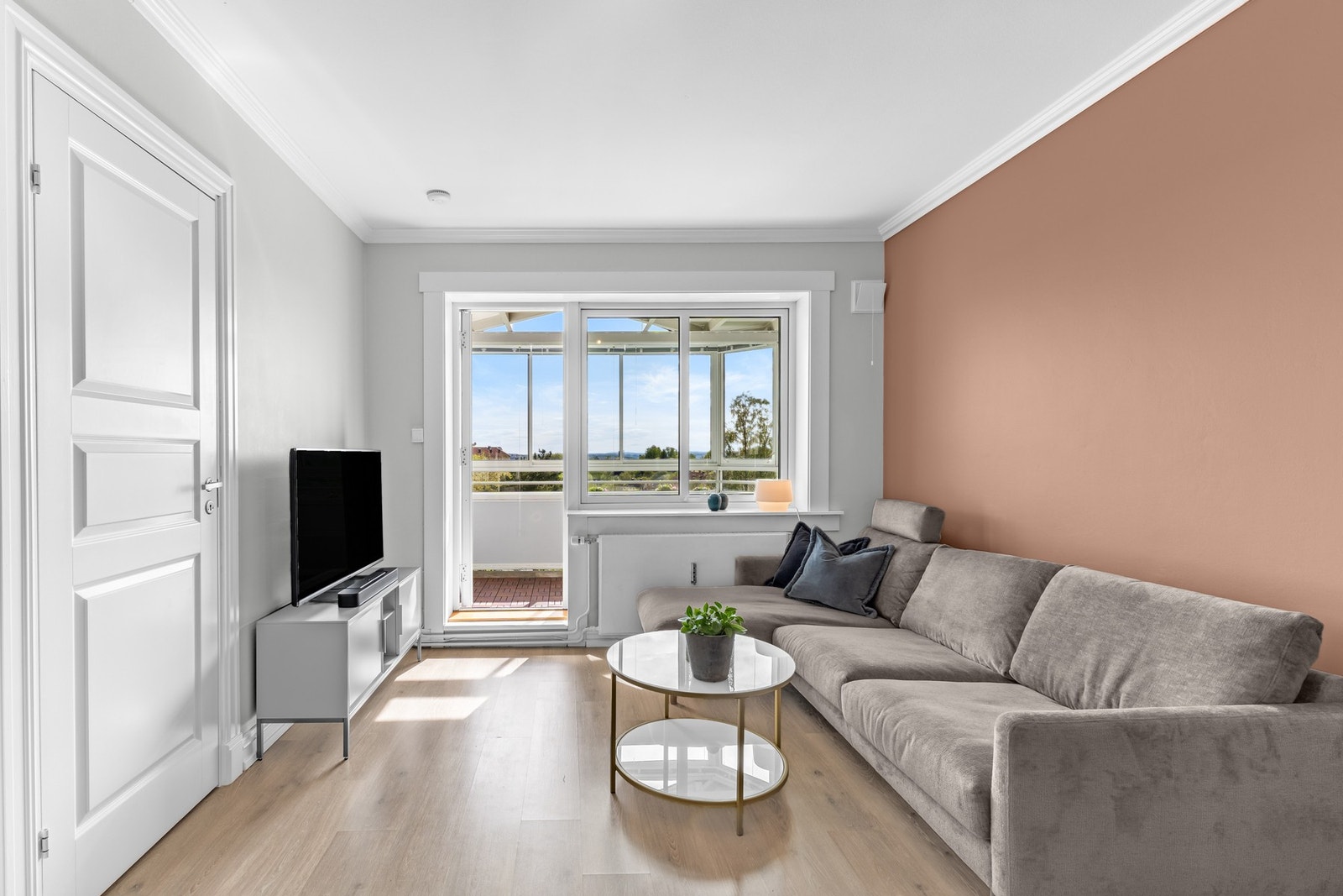 En åpen og behagelig stue hvor store vinduer slipper inn rikelig med dagslys. Galleribilde