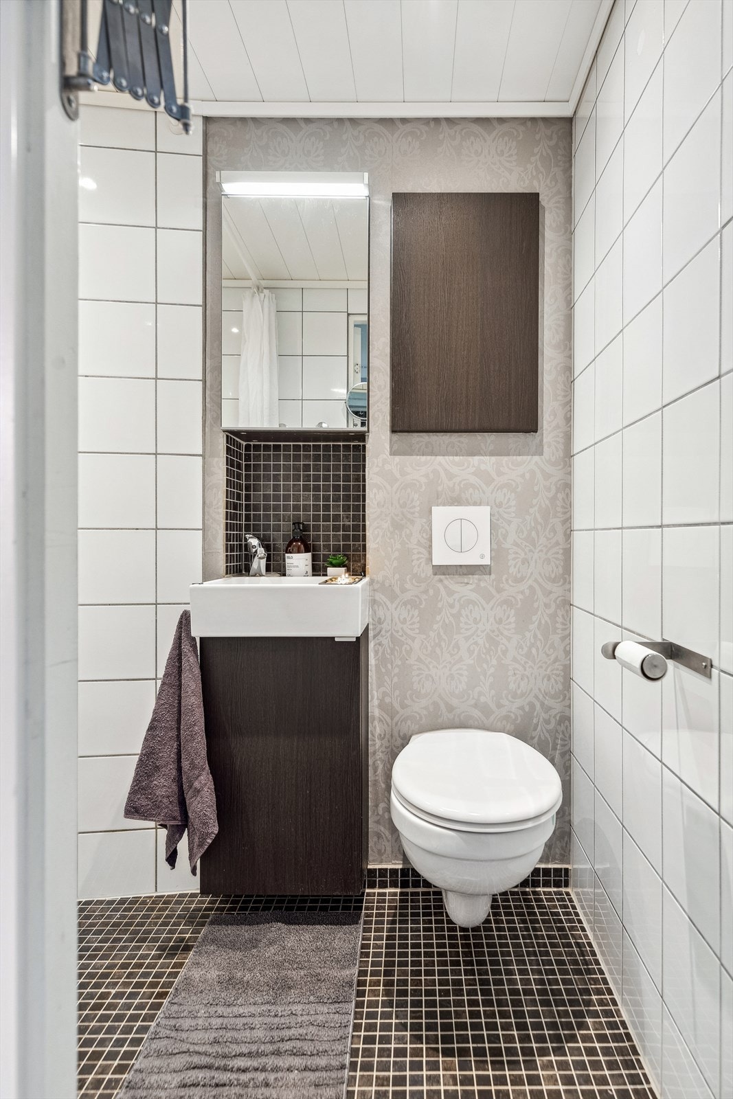 Badet er utstyrt med blant annet vegghengt toalett, servant med underskap, speilskap og dusjhjørne. Galleribilde