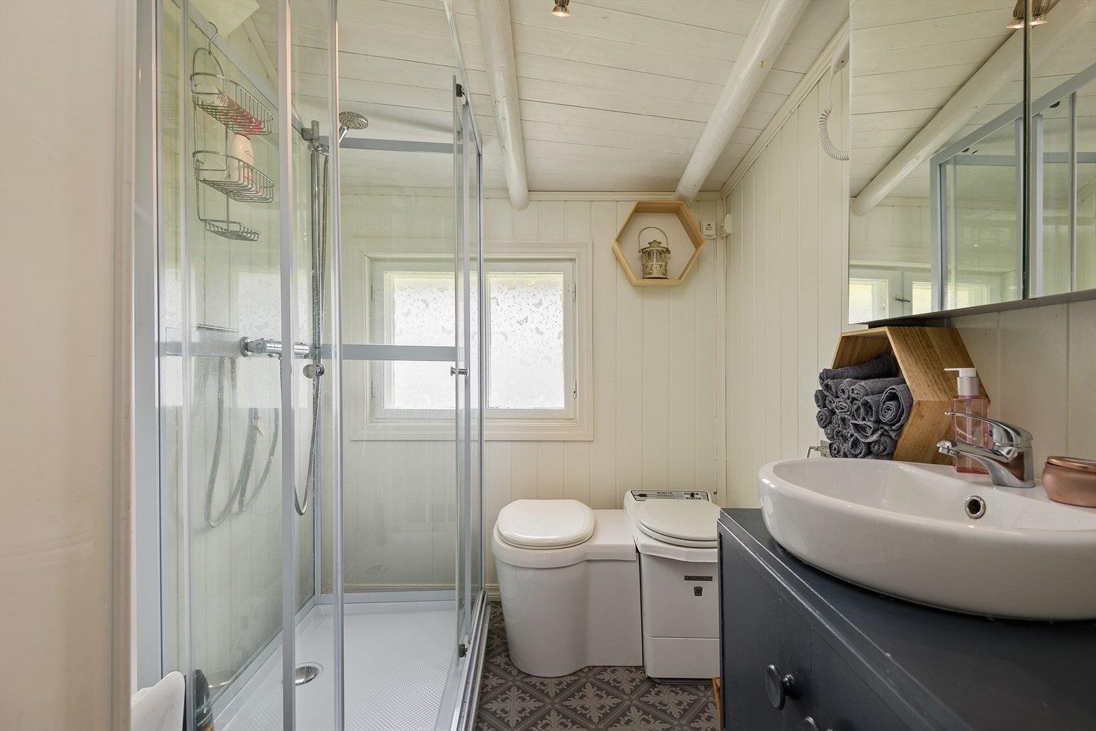 Badet ble oppgradert i 2019, men er ikke bygd som et komplett våtrom. Badet er utstyrt med baderomsinnredning, forbrenningstoalett, urinal og dusjkabinett Galleribilde