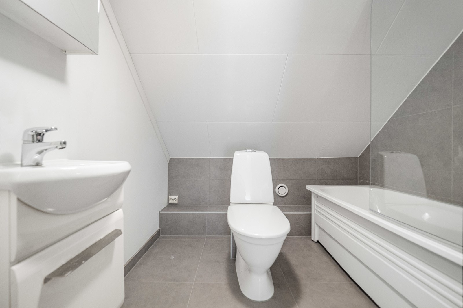 Badet i andre etasje ble pusset opp i 2025 og fremstår som moderne, med grå fliser, hvit innredning og badekar. Galleribilde