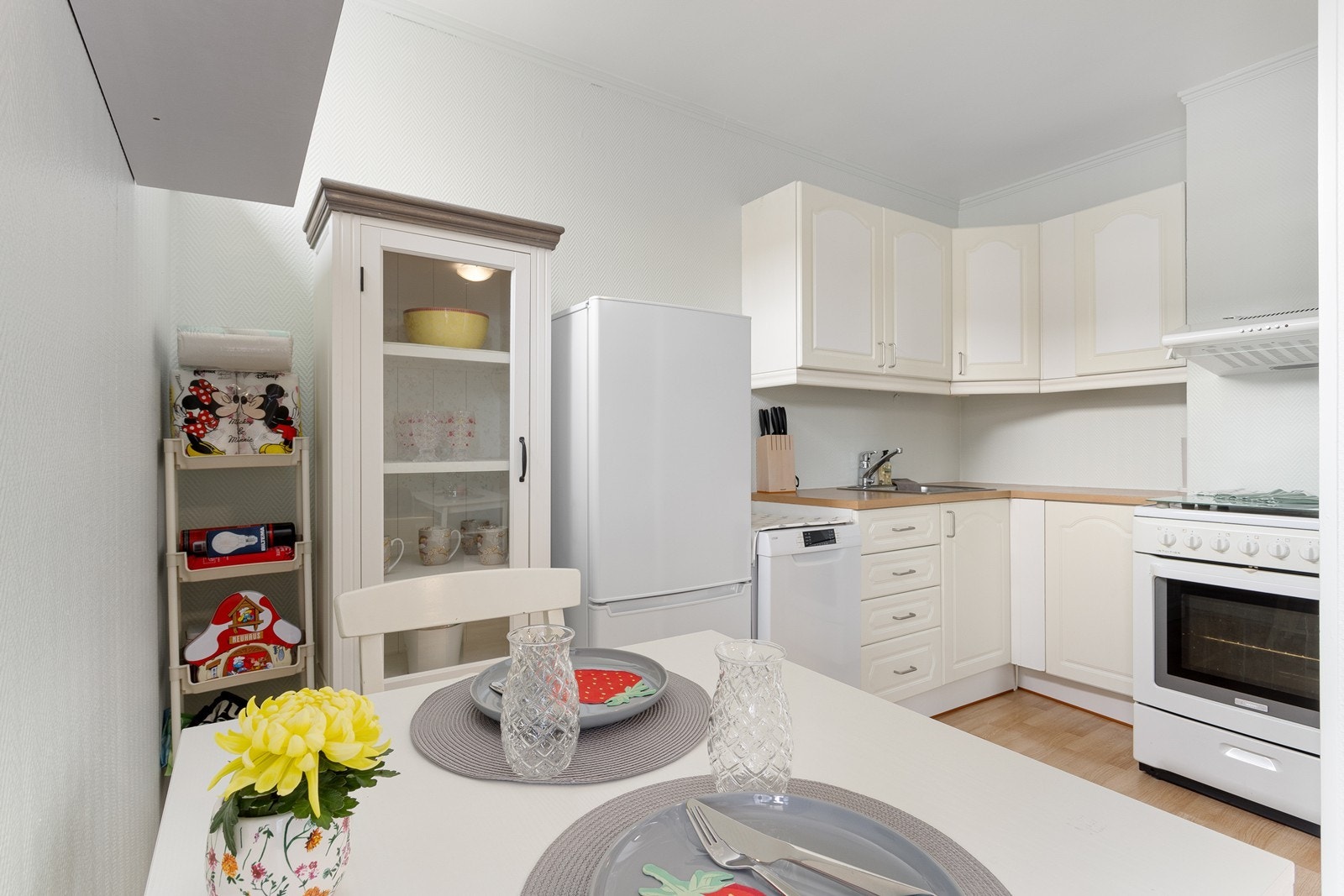 Kjøkkenet inneholder en profilert skapinnredning med lyse fronter og frittstående hvitevarer. Galleribilde