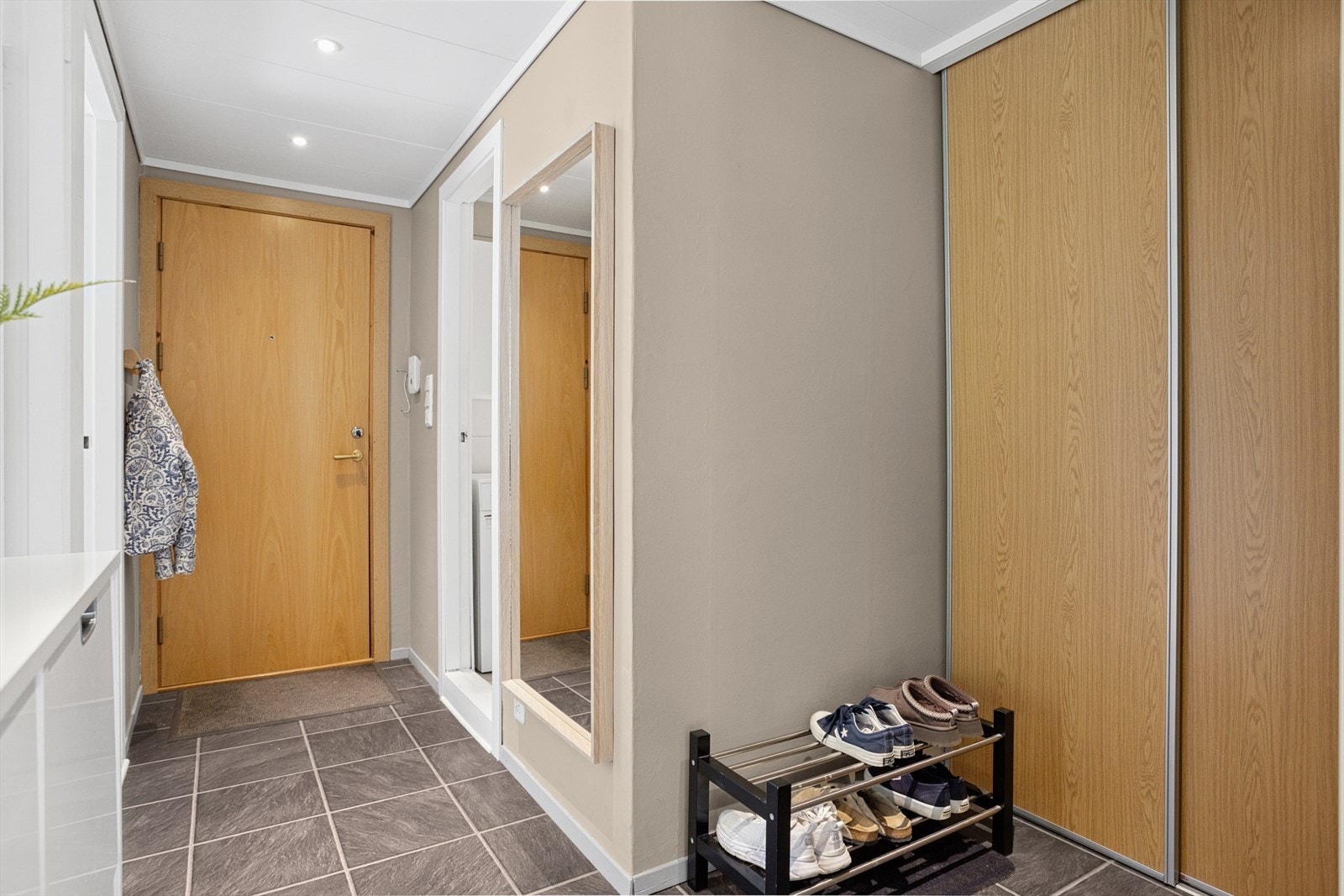 Innbydende og romslig entré som gir et flott førsteinntrykk av leiligheten. Her er det god plass for oppheng av jakker og sko, noe som bidrar til å holde området ryddig og organisert. Galleribilde