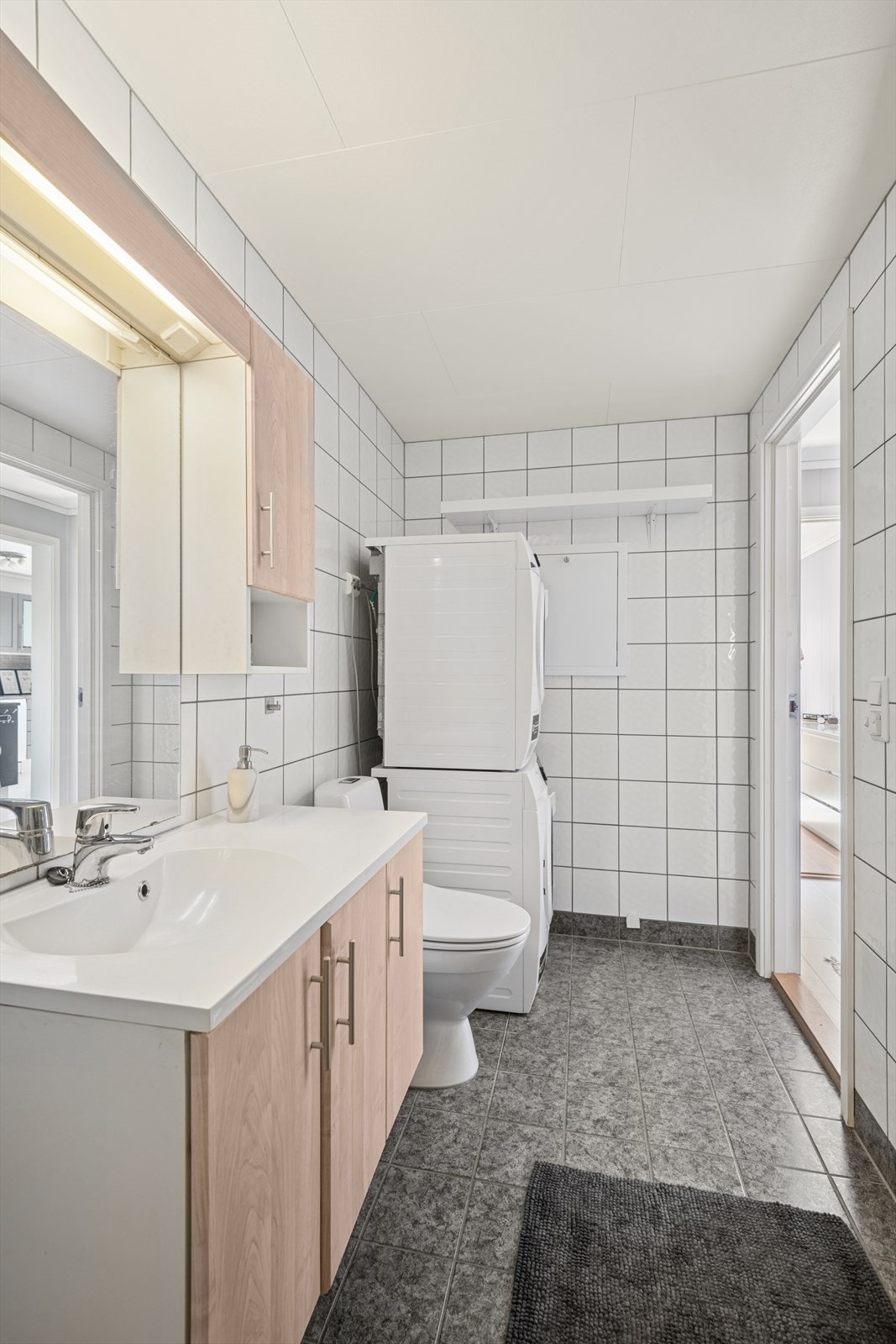 Badet er et kombinert bad/vaskerom med flislagte overflater på både gulv og vegger. Varmekabler. Galleribilde