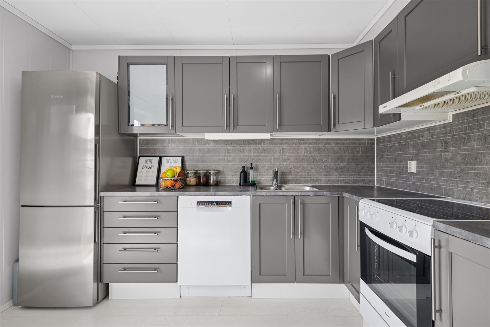 Innredningen i rommet er utført med laminerte skrog, mørke glatte fronter og laminert benkeplate med kjøkkenkum. Galleribilde