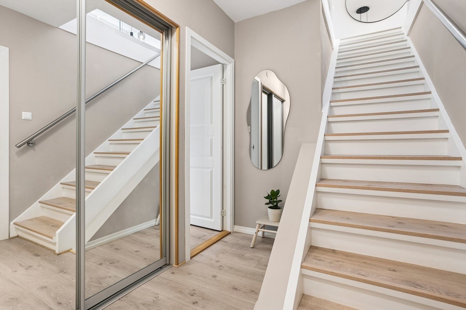 I leilighetens entré er det en stor skyvedørsgarderobe med speilfronter. Inngang til det ene soverommet og trapp opp mot øverste etasje Galleribilde