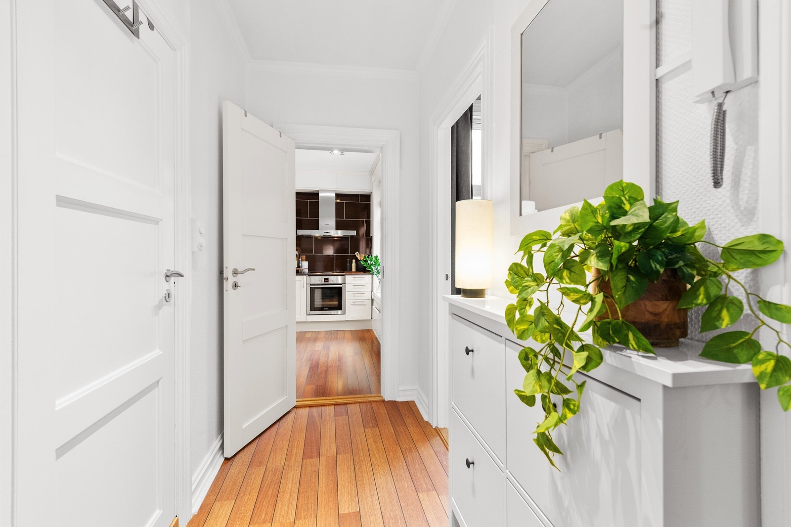 Lys og innbydende gang som leder inn til et moderne kjøkken. Perfekt for deg som ønsker et stilrent hjem. Galleribilde