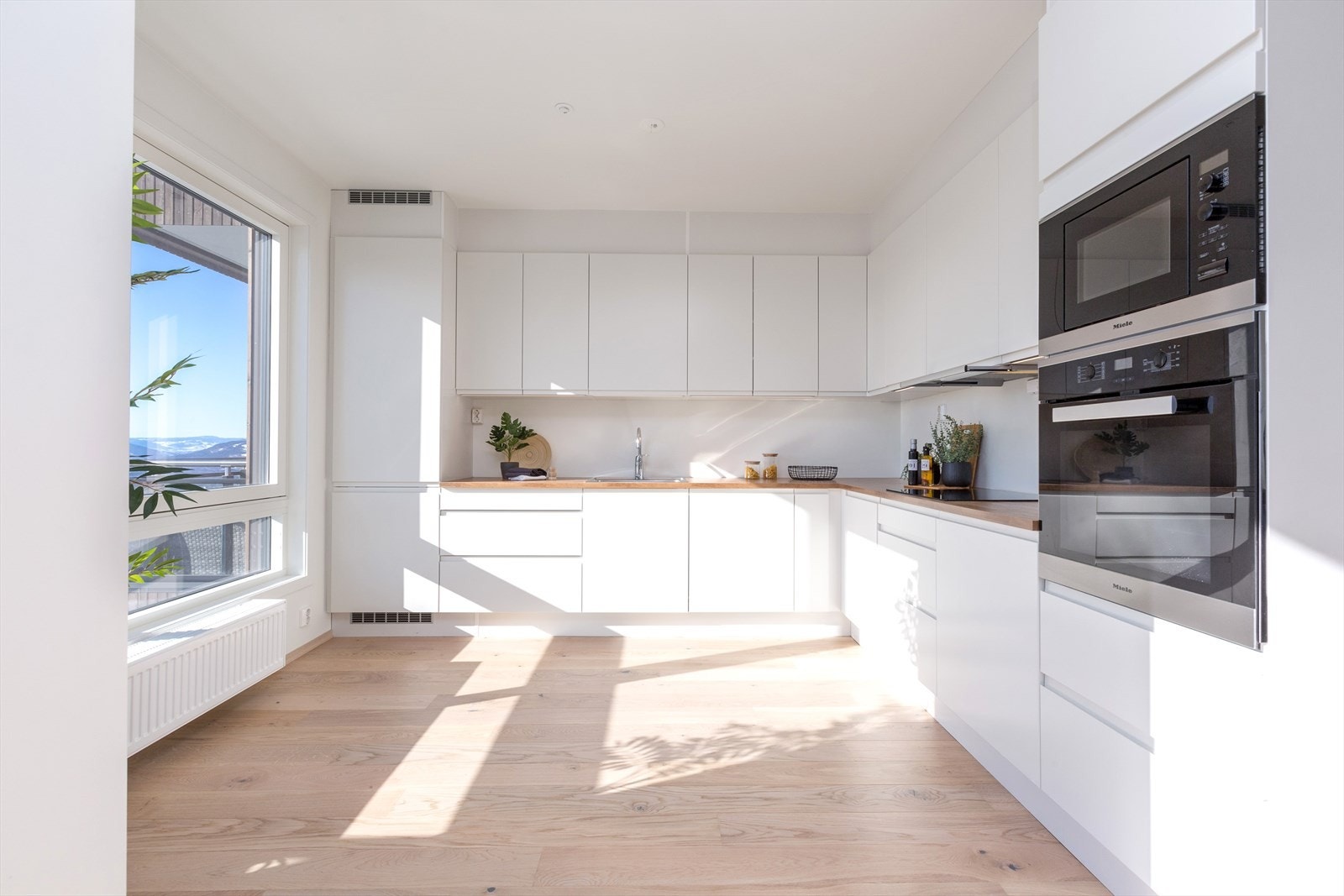 Delikat kjøkken med glatte fronter og laminat benkeplate med oppvaskkum. Galleribilde