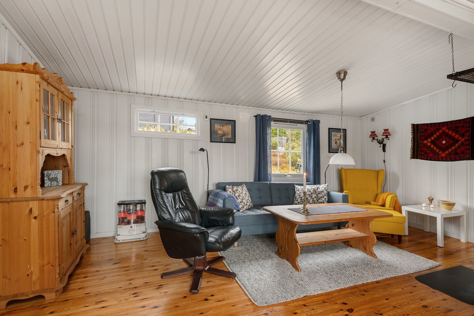 Oppholdsrommet har lakkert tregulv og vegger og tak som er malt i hvit farge. Galleribilde