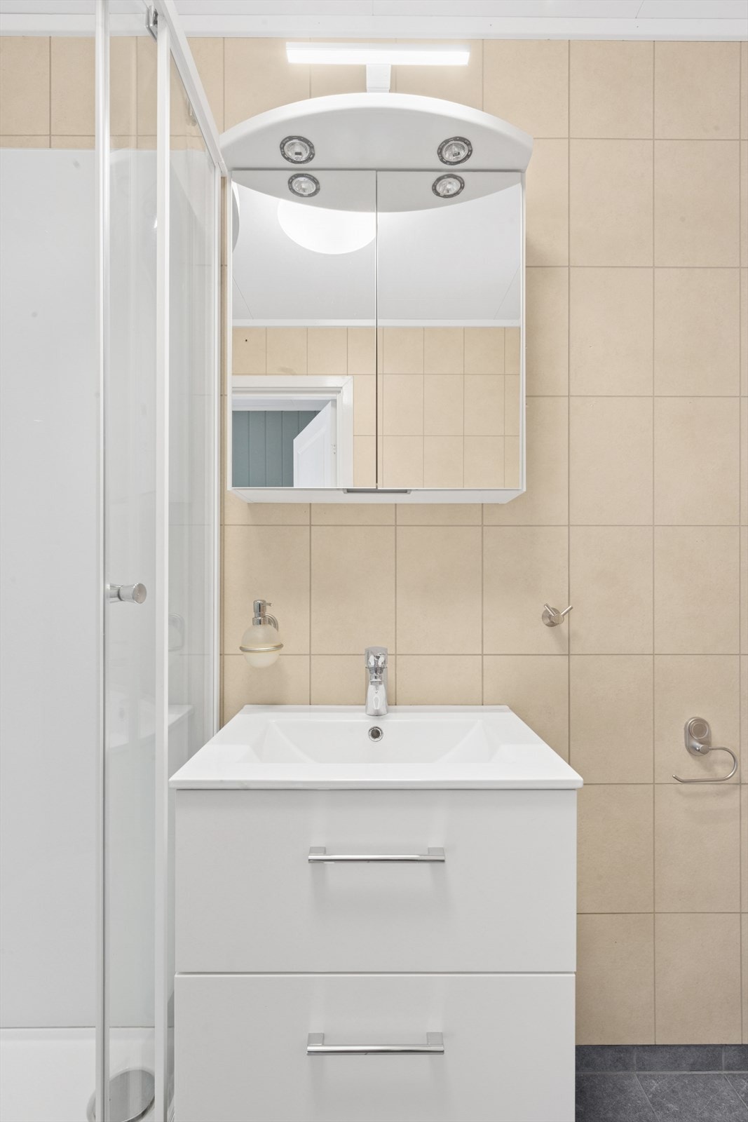 Baderommet er innredet med servant og servantskap, gulvmontert toalett og dusjkabinett. Opplegg for vaskemaskin. Galleribilde