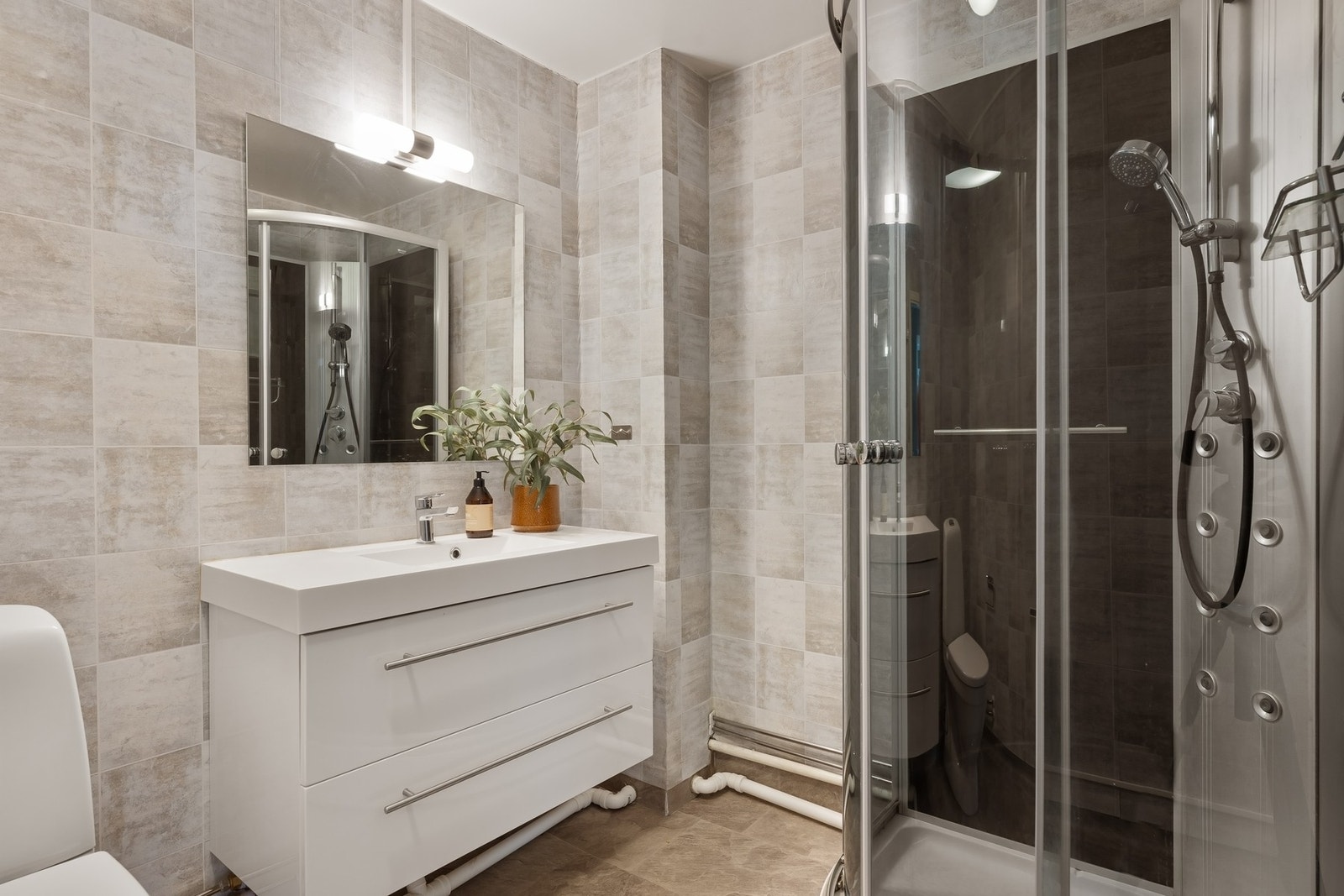 Praktisk bad med dusjkabinett, toalett og servant med underskap. Galleribilde