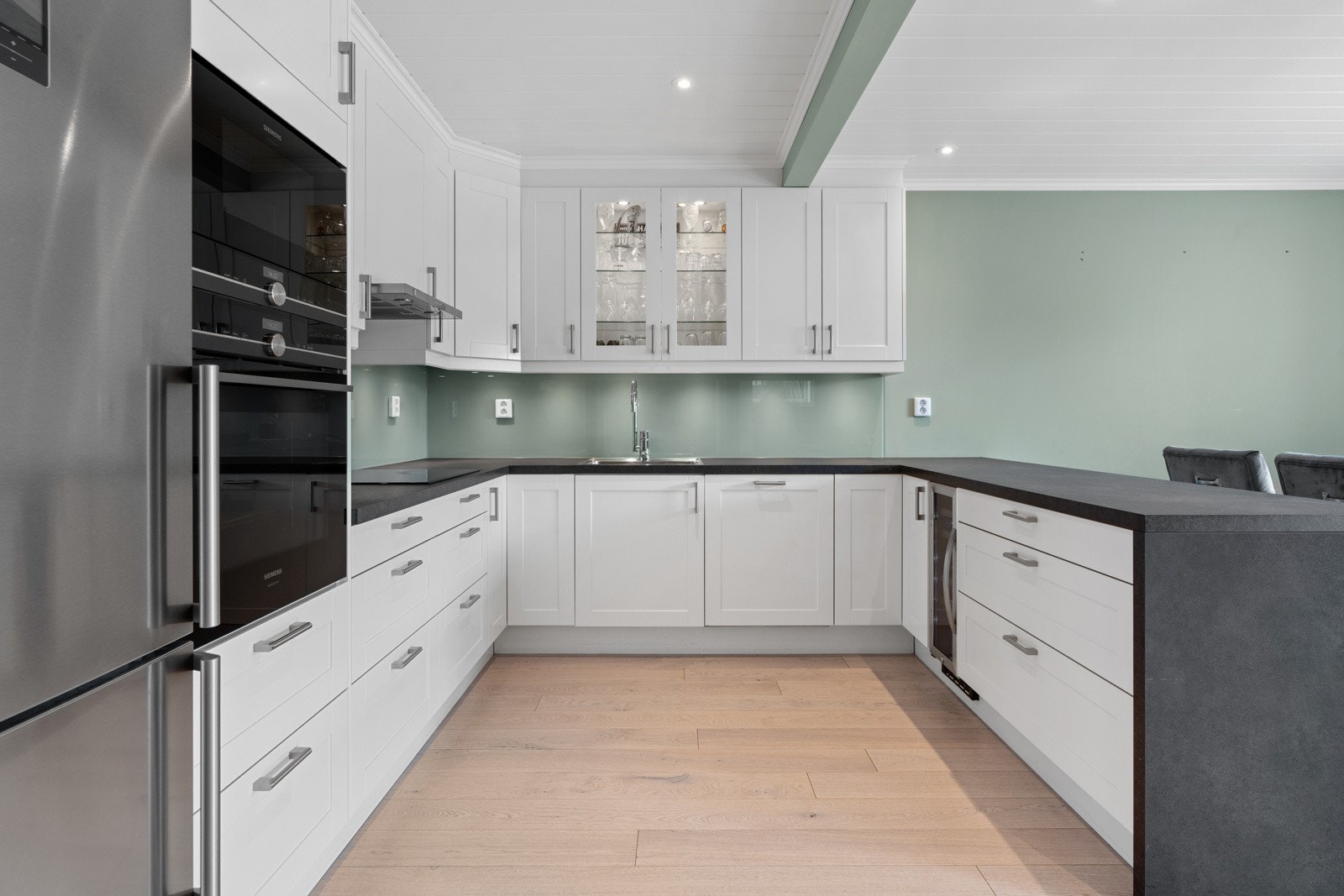 Kjøkkenet er stilrent og moderne med profilerte fronter i hvit-utførelse og laminat benkeplate. Galleribilde