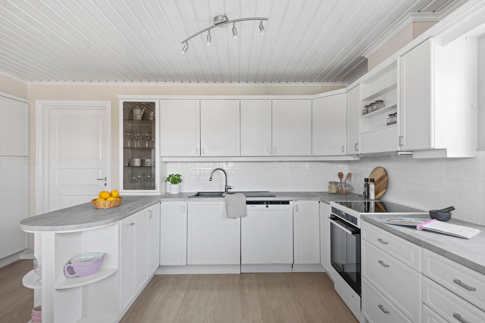 Kjøkkenet er med kjøkkeninnredning i malt profilert utførelse. Foliert laminat benkeplate med fliser over benk. Galleribilde