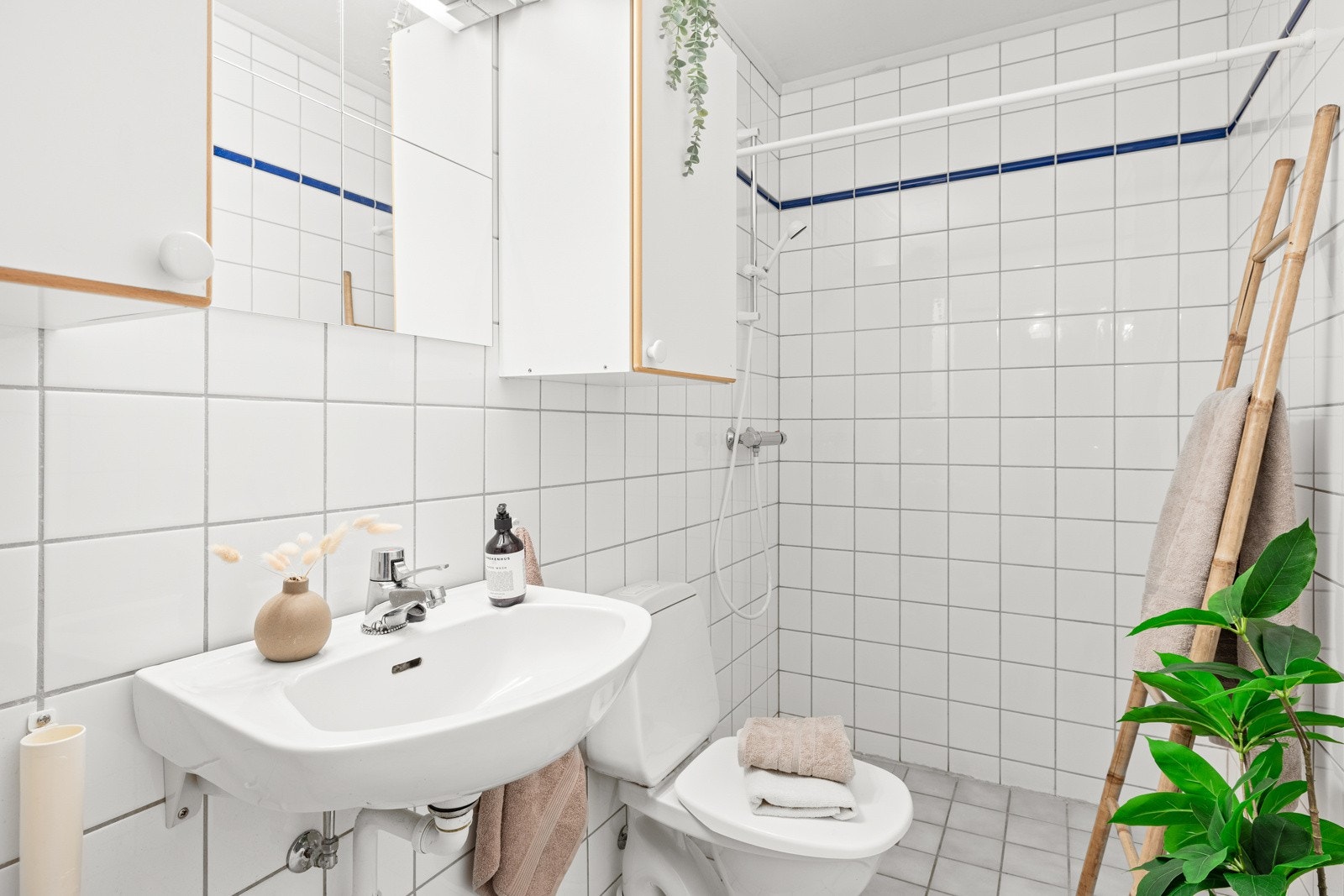 Det flislagte badet er fra 1994 og er innredet med servant, veggskap, speil med lys, toalett, dusj og opplegg til vaskemaskin. Galleribilde