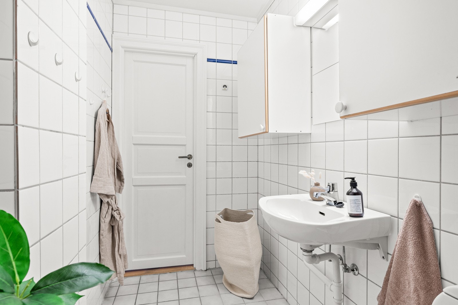 Det flislagte badet er fra 1994 og er innredet med servant, veggskap, speil med lys, toalett, dusj og opplegg til vaskemaskin. Galleribilde