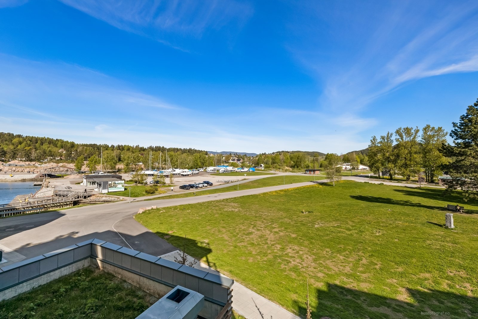 Utsikt utover vannkanten, brygge og grøntarealer. Galleribilde