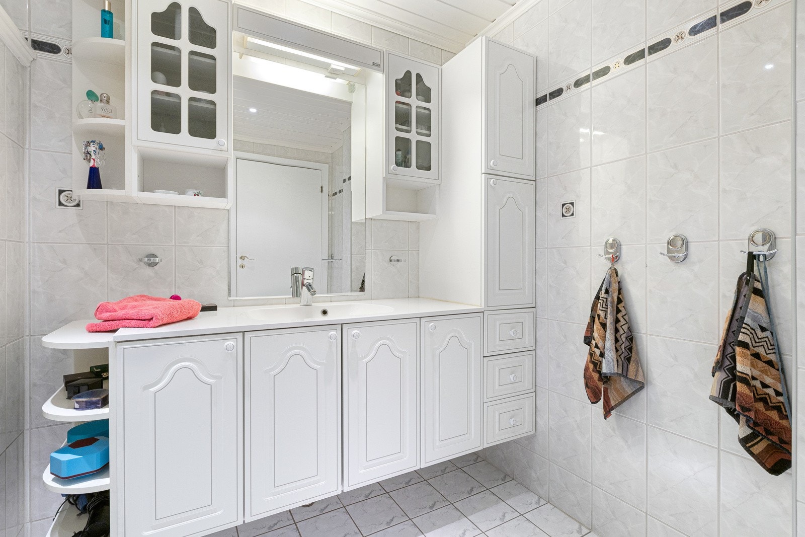 Badet har nisje og opplegg for vaskemaskin, servant med ettgreps kran og med skap under. Høyskap på høyre side og speil over servanten Galleribilde