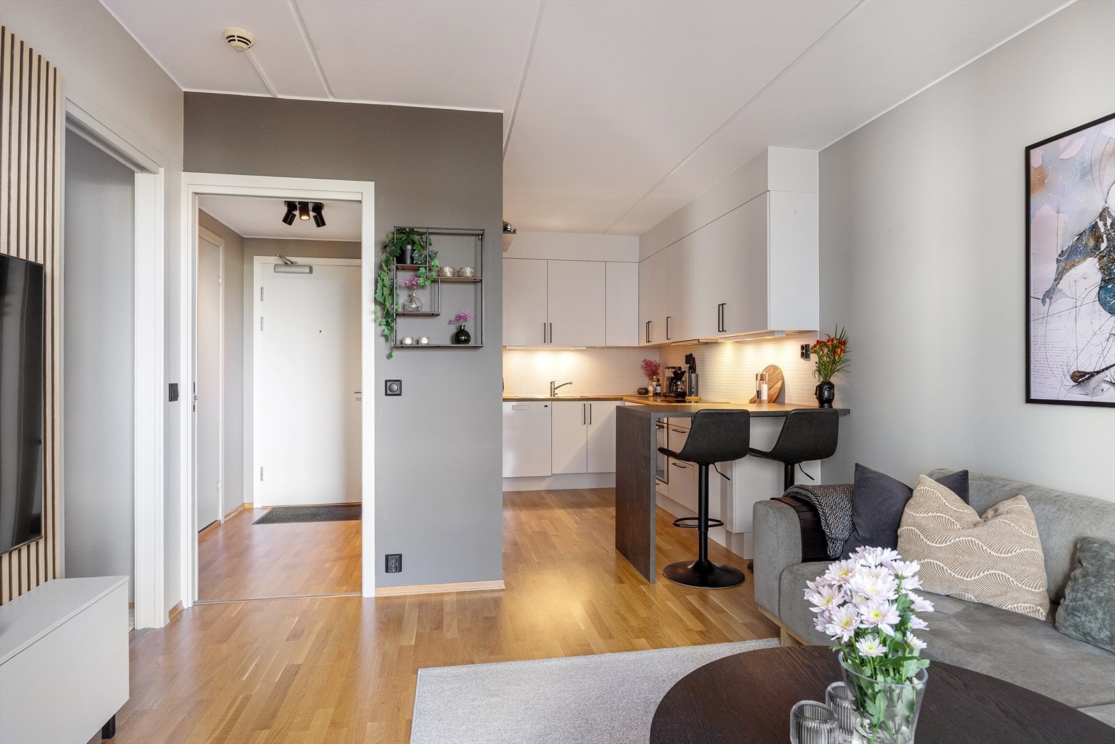 Leiligheten har en luftig, delvis åpen løsning mellom stue og kjøkken, hvor kjøkkenet ligger i en egen nisje. I kjøkkenenden er det plassert en praktisk bar som fungerer både som romslig arbeidsflate og koselig spiseplass. Galleribilde