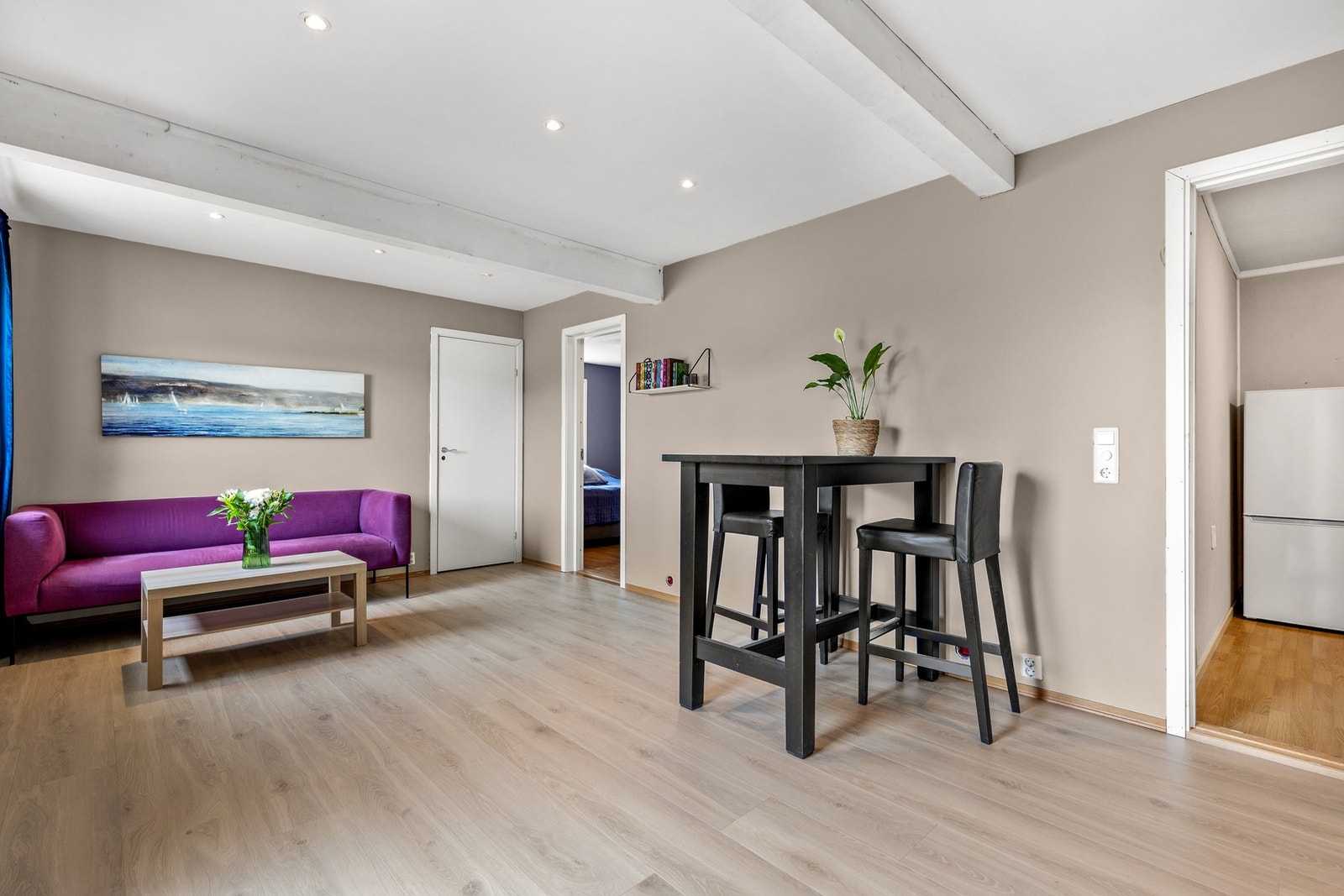 Lys stue med laminat på gulv, slette vegger og downlights i himling. Rommet har fin plass til sofa og spisebord. Galleribilde