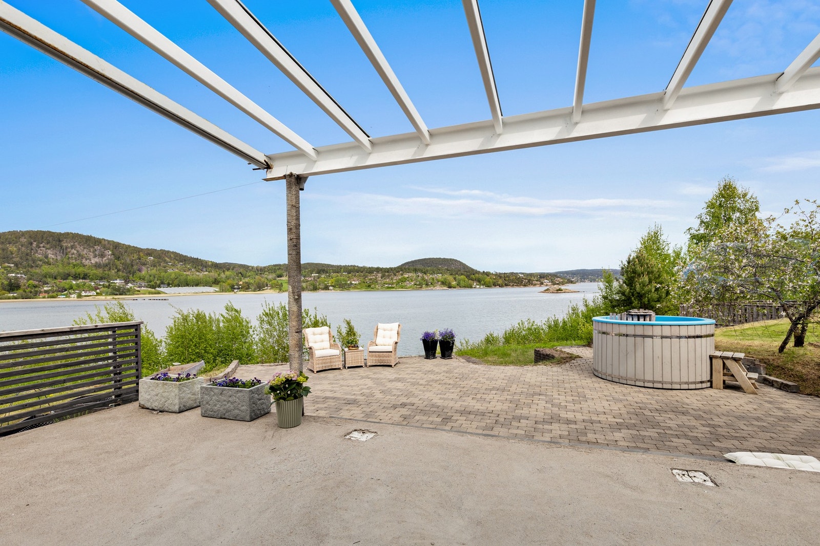 Eiendommen har flere uteplasser rundt boligen. Her kommer man ut fra stuen til en meget romslig og solrik uteplass med fantastiske solforhold. Galleribilde