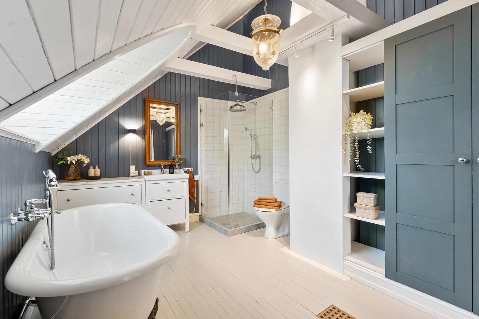 Den ene veggen har plassbygde skap med blåmalte fronter og en innebygd håndklehylle. Badet har også opplegg for vaskemaskin og tørketrommel. Galleribilde