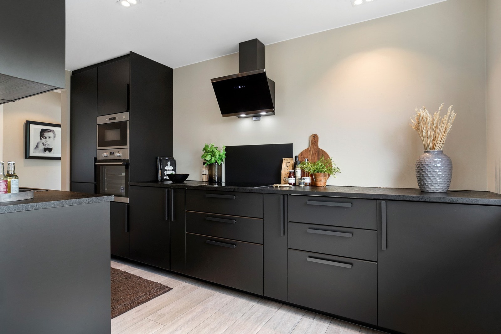 Stilrent kjøkken med sorte fronter, godt med benkeplass og integrerte hvitevarer Galleribilde