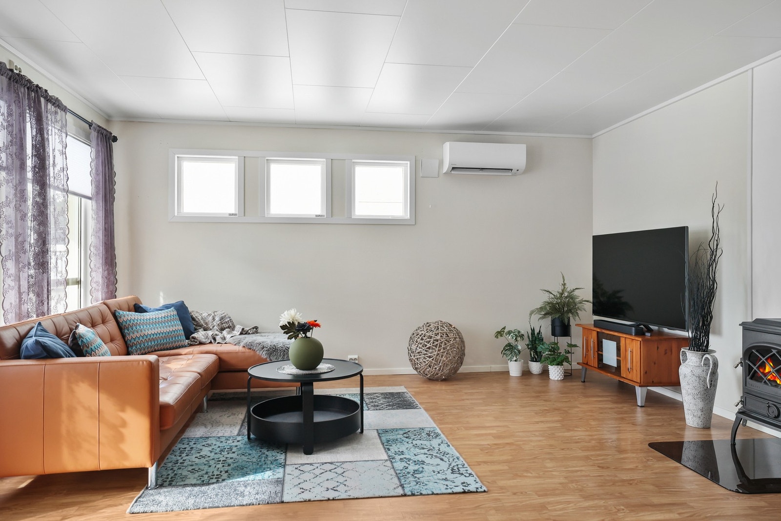 En vedovn bidrar med en varm og hyggelig atmosfære, mens varmepumpen på veggen sørger for praktisk og effektiv oppvarming Galleribilde