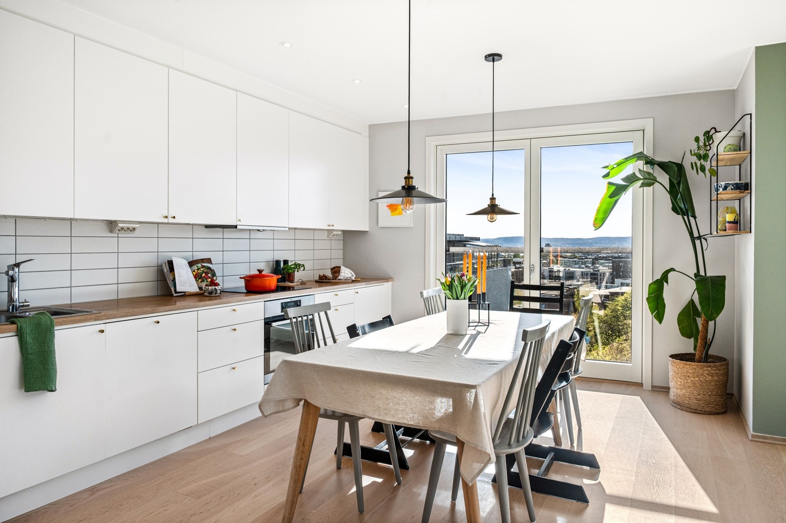 Kjøkkenet har hvite, glatte fronter som gir et rent og tidløst uttrykk, kombinert med benkeplater i eik som tilfører varme og naturlige kontraster. Galleribilde