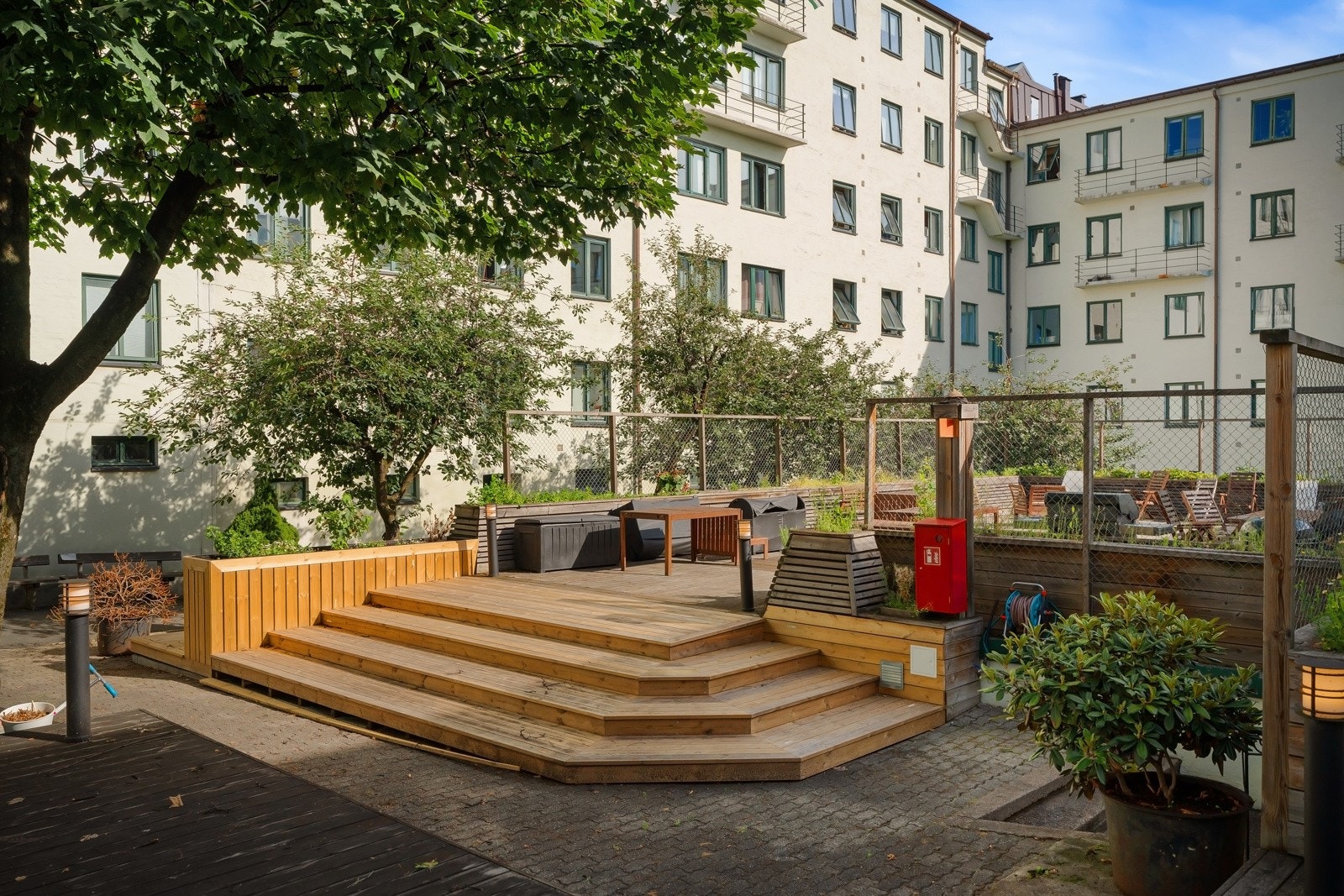 Supertrivelig og barnevennlig bakgård med sittegrupper, beplantning og lekeplass. Galleribilde