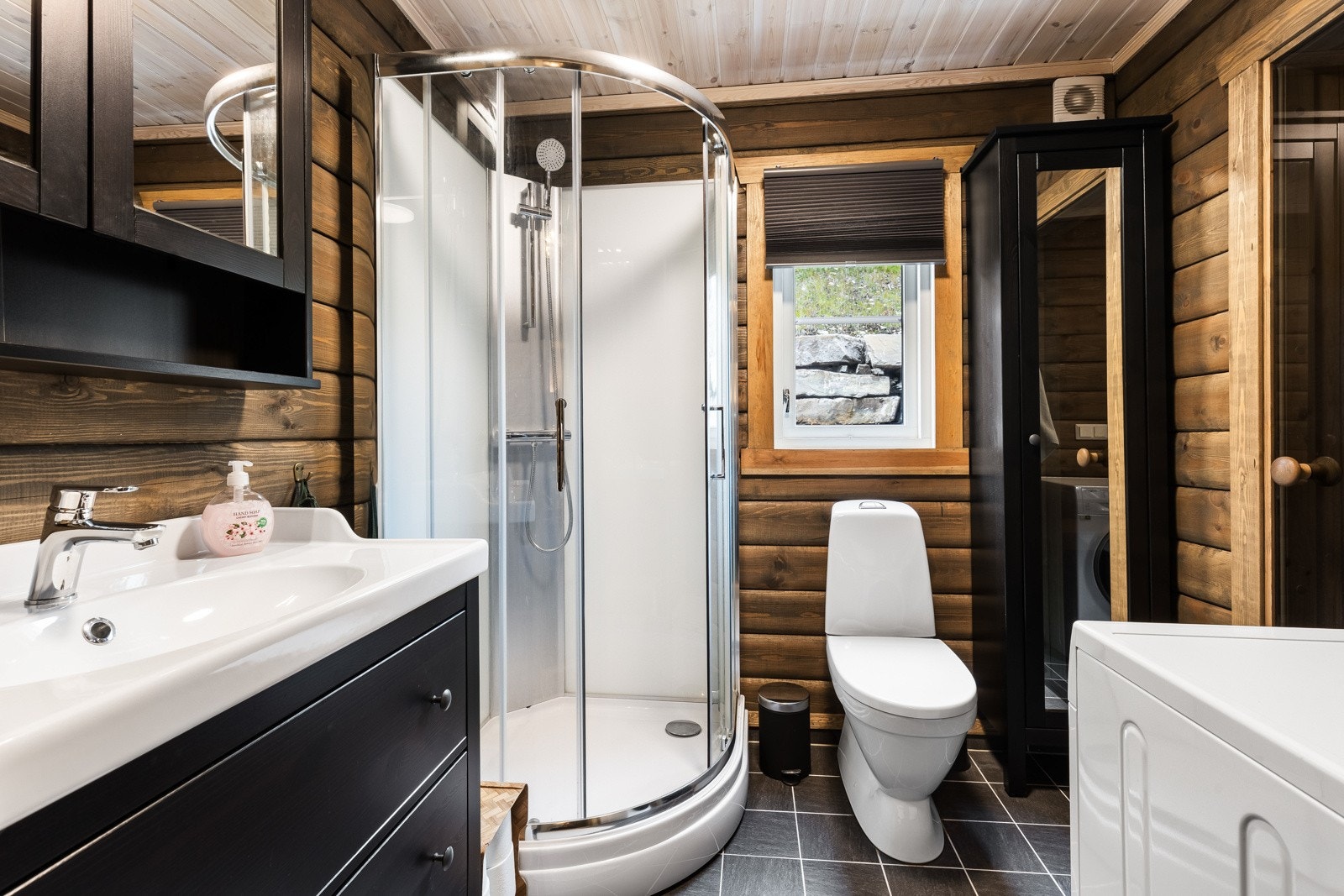 Badet er delikat med sorte gulvfliser, varmekabler og laftede vegger. Galleribilde