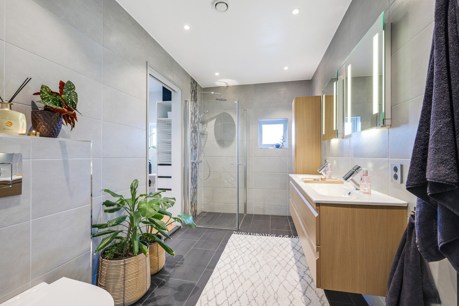 . Innredningen er fra Foss bad, og det er dobbel servant med eikeskuffer, matchende høyskap og to speil med integrert belysning over servantene. Galleribilde