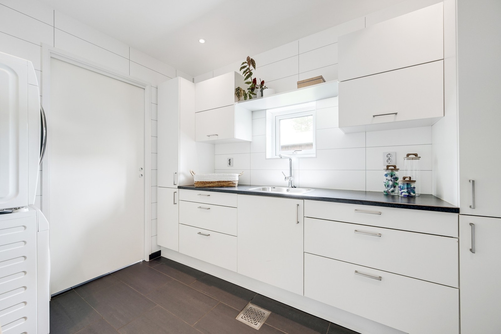 Fra kjøkkenet er det videre adkomst til et hendig vaskerom. Vaskerommet ligger i tilknytning til en bod med egen utgang til eiendommen. Galleribilde