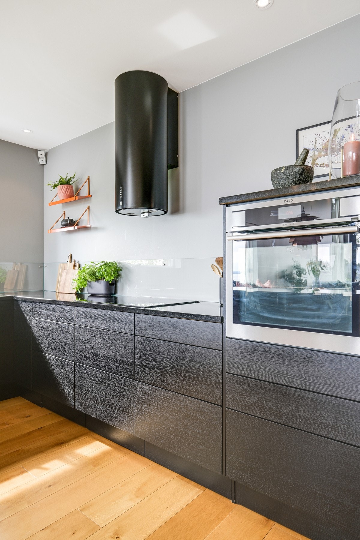 Glassplater er montert over benken, og over kokesonen har kjøkkenet en stilig ventilator i sort utførelse. Galleribilde