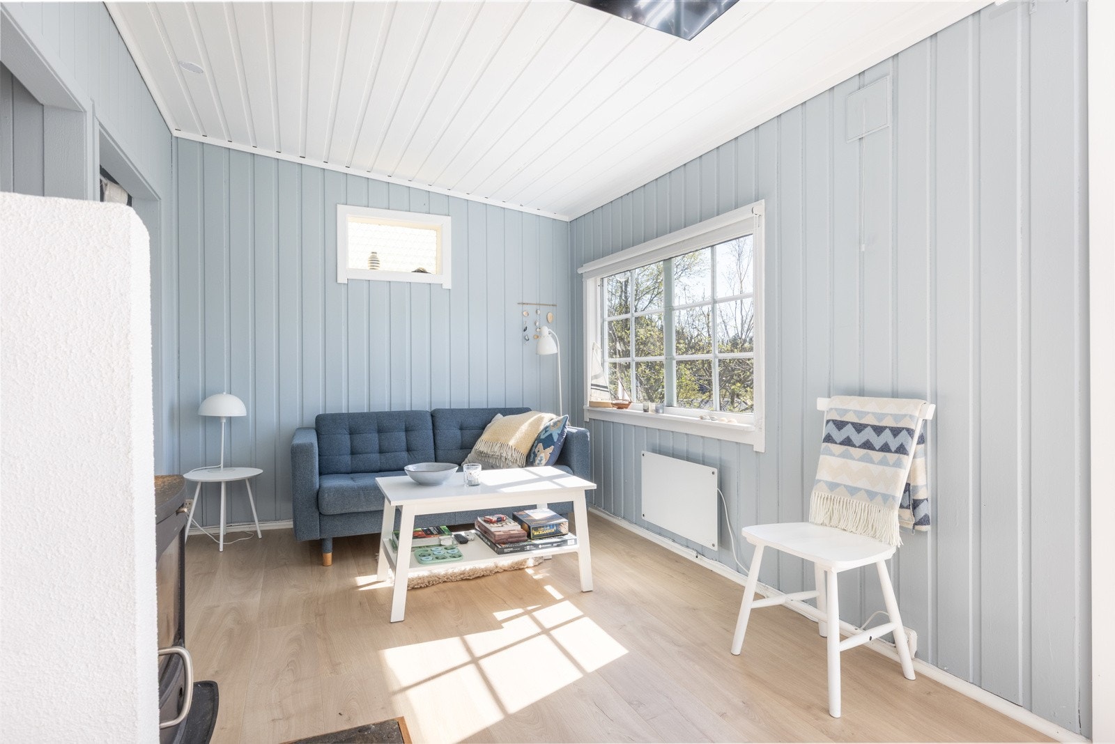 Stuen har god takhøyde, store vinduer og en rolig, sommerlig atmosfære Galleribilde