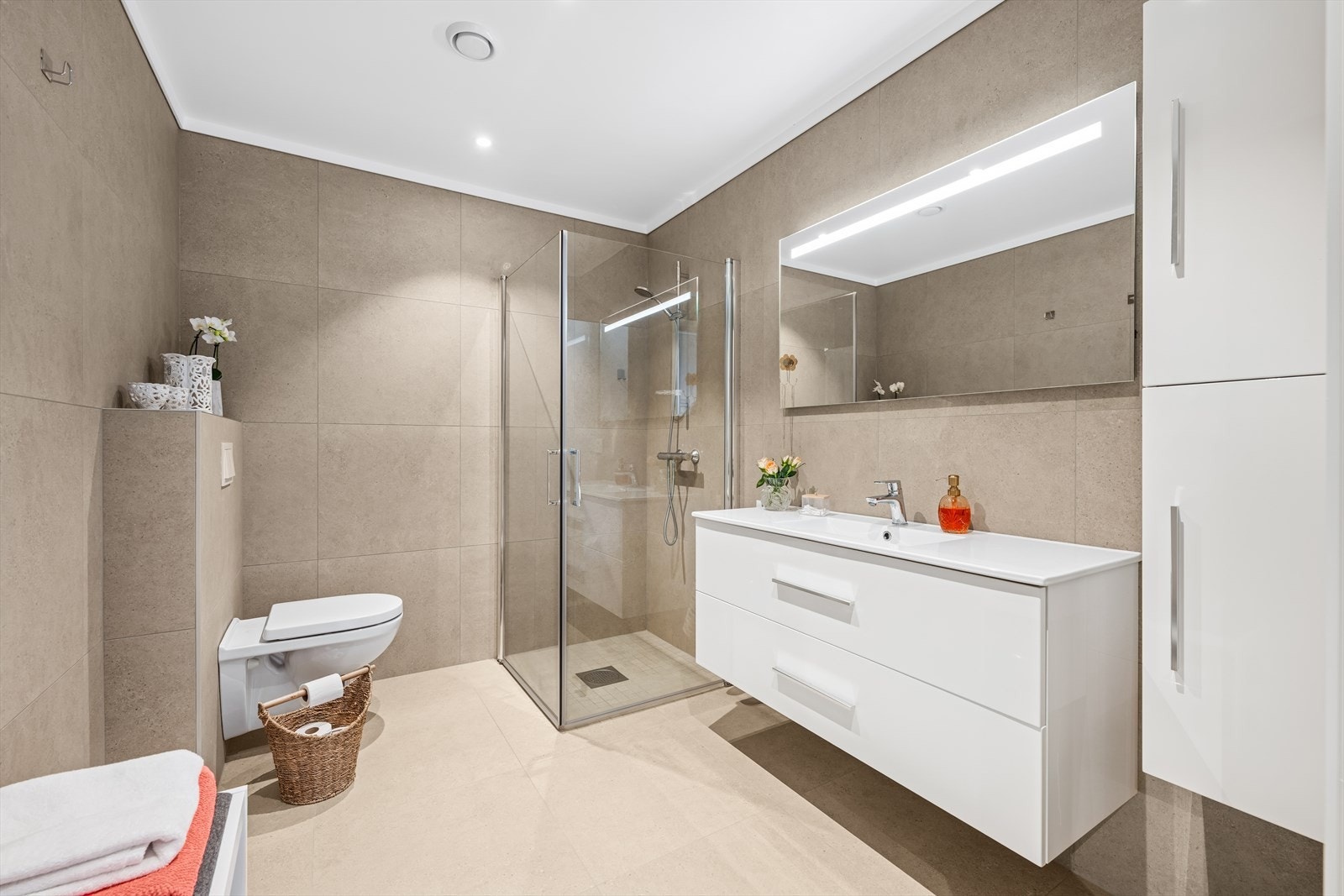 Delikat og tidskorrekt baderom med flislagt gulv og nedsenket gulv i dusj. Dusjhjørne med innfellbare glassdører, vegghengt WC og lekker baderomsinnredning med servant og lyssatt speil over. Galleribilde