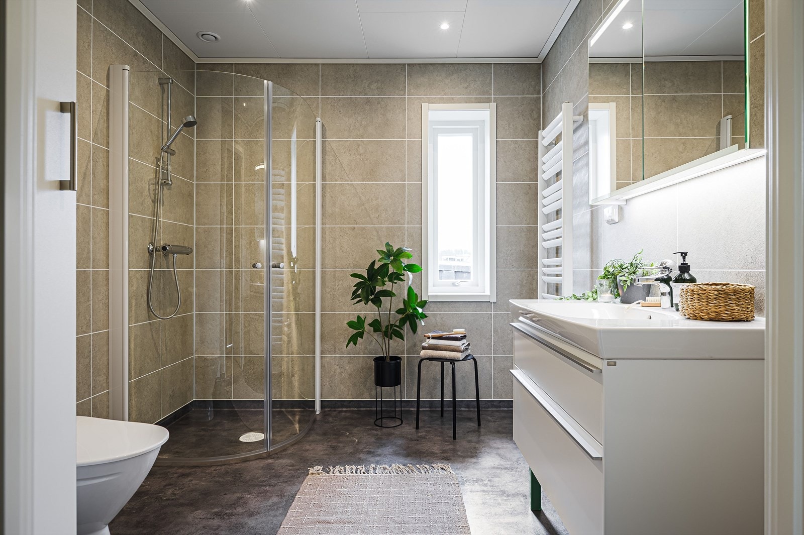 Moderne baderom 1 fra 2024 med belegg på gulv med gulvvarme, våtromsplater på veggene, downlights i himlingen og balansert ventilasjon. Håndklehenger med vannbåren varme. Galleribilde