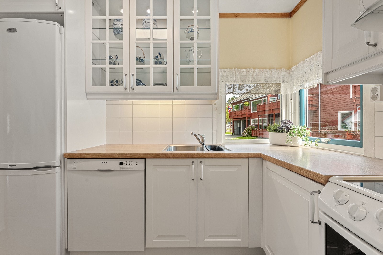 Kjøkkeninnredning med hvite fronter og laminert benkeplate med planlimt kjøkkenvask. Galleribilde