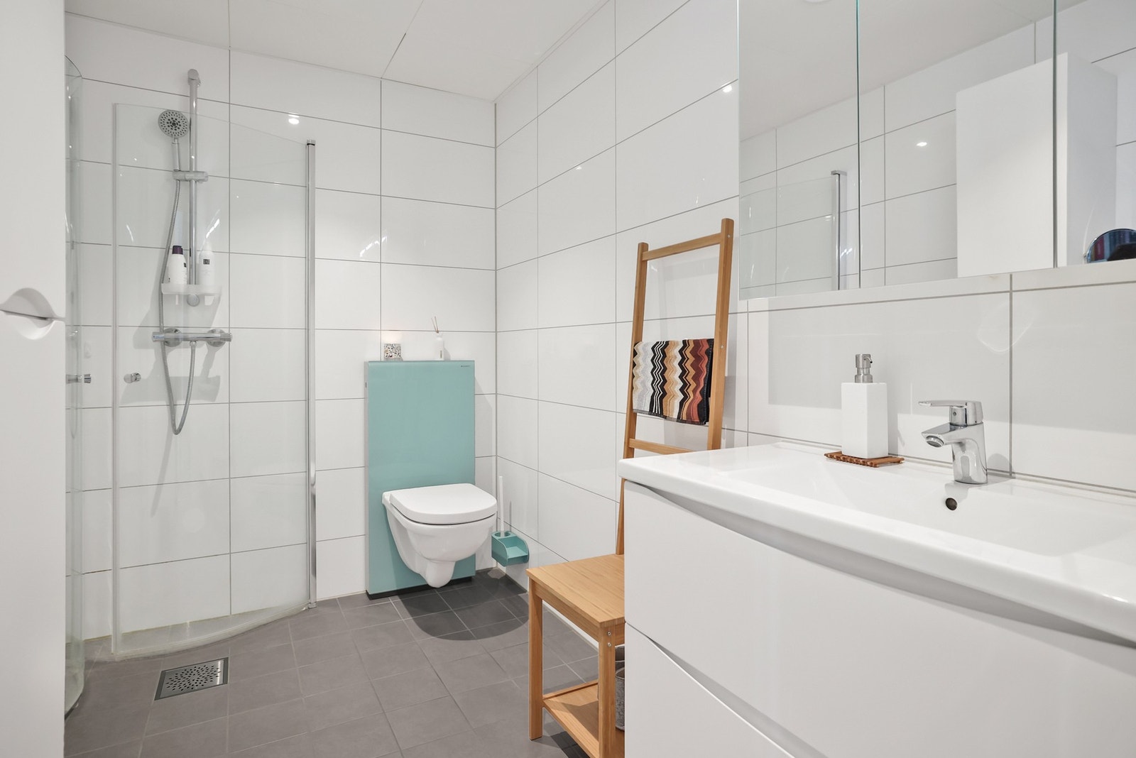 Badet er moderne med helfliselagte overflater, gulvvarme, dusjhjørne og servant med speilskap. Galleribilde