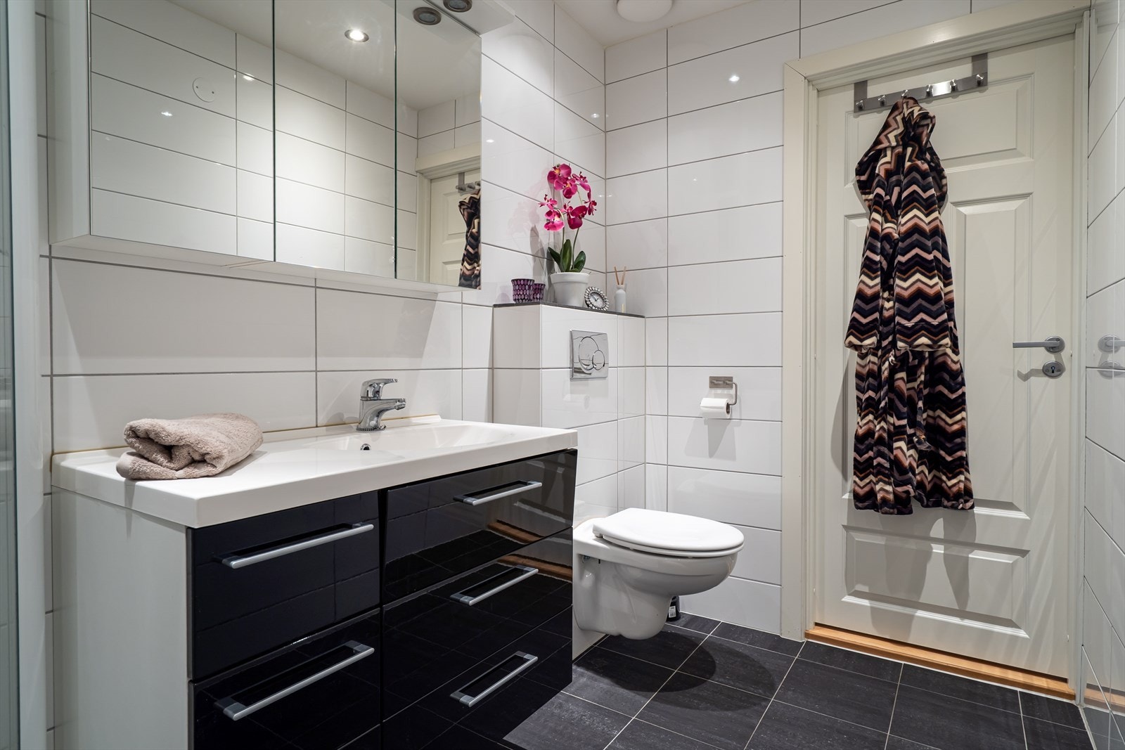 Badet ligger i andreetasje sammen med soverommene. Badet holder god standard med fliser på gulv og vegger, baderomsinnredning, dusjhjørne og vegghengt toalett. Galleribilde