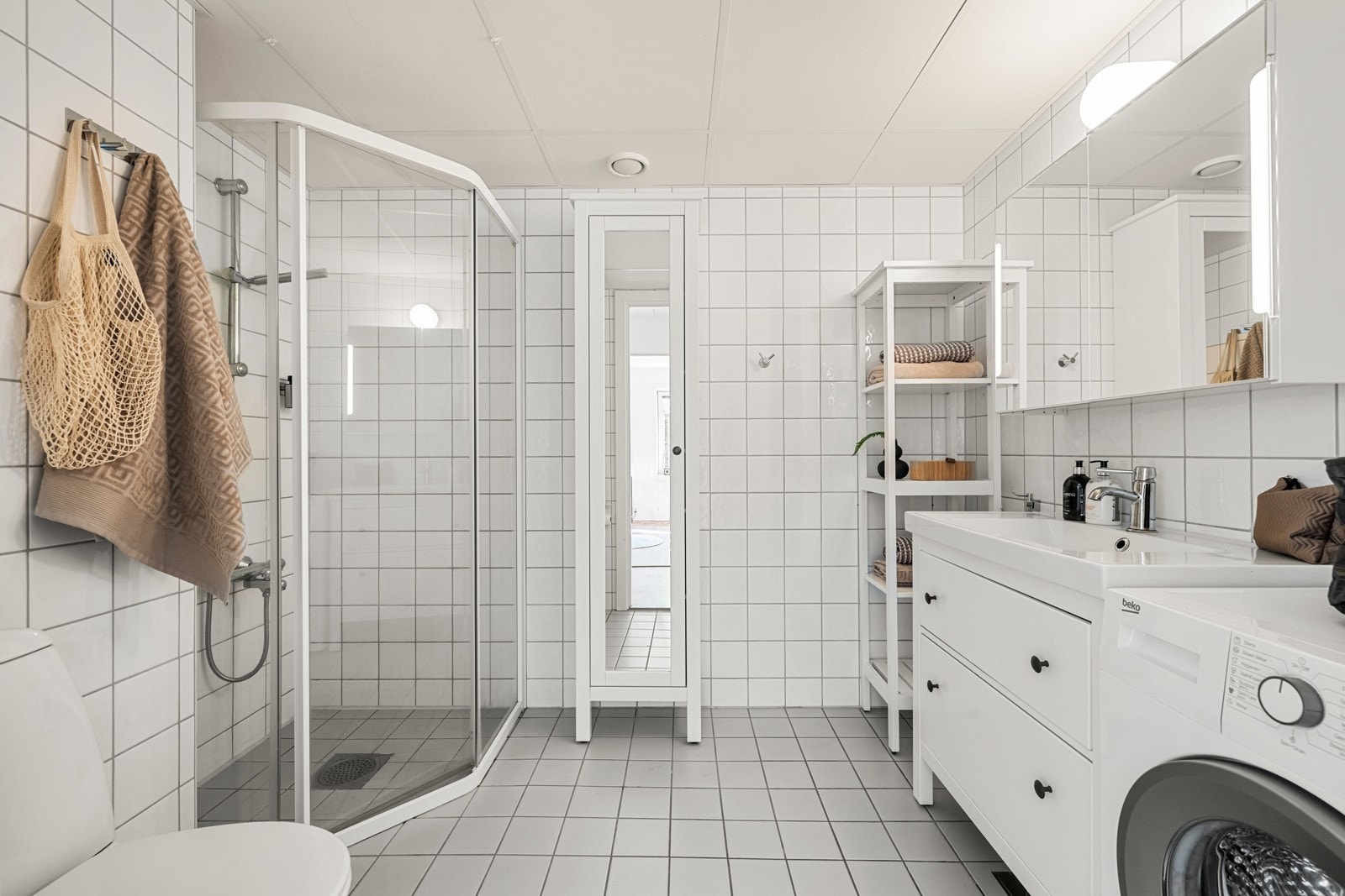 Romslig baderom med flislagte overflater, gulvvarme og opplegg for vaskemaskin Galleribilde