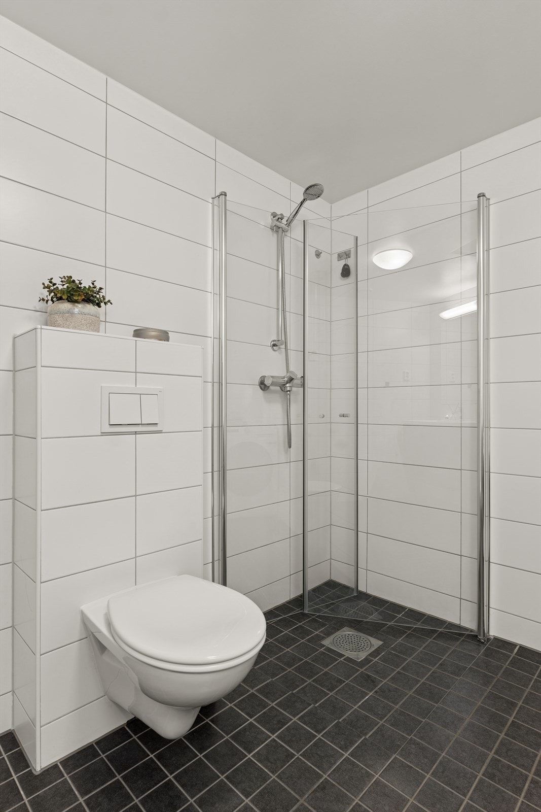Badet har mørke fliser på gulv med behagelig gulvvarme og hvite fliser på vegg. Galleribilde