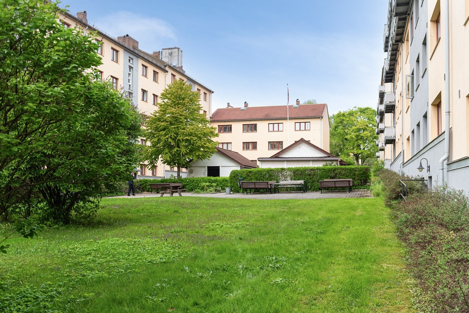 Idyllisk og hyggelig felles hage med plen og sittegrupper Galleribilde