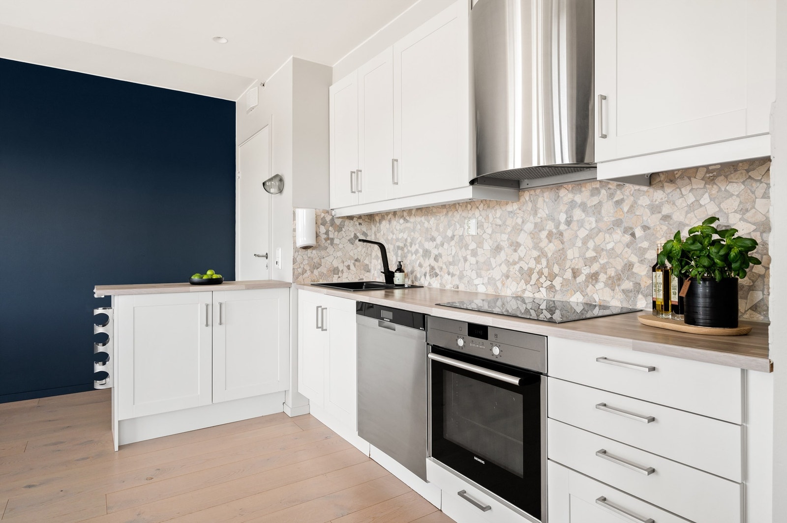 Det er montert fliser mellom benkeskap og overskap i tillegg til benkeskapsbelysning og stikkontakter under overskap. Samtlige hvitevarer medfølger. Galleribilde