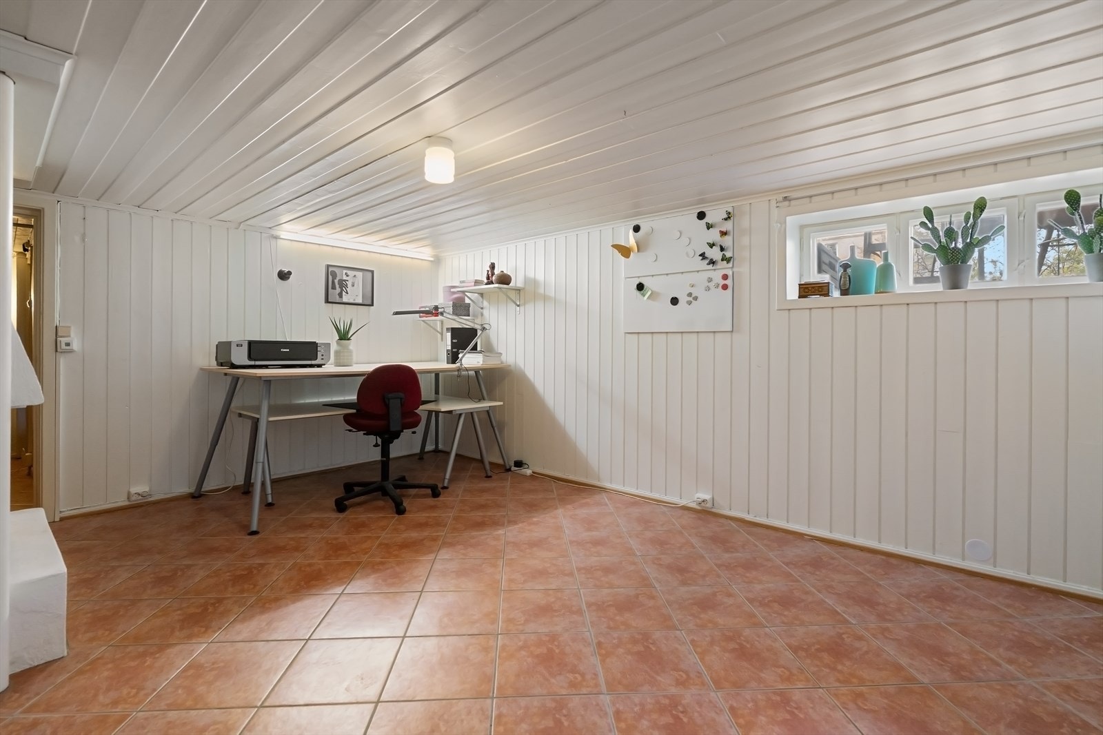 Rommet har flislagt gulv, panelte overflater og peisinnsats. Galleribilde